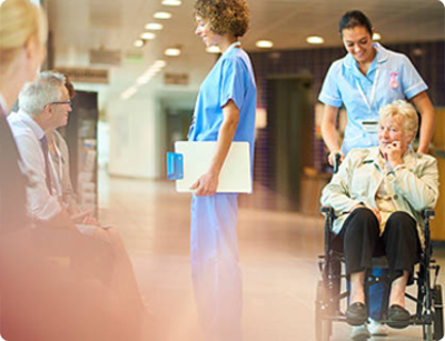Health care professionals assisting patients in a hospital hallway.