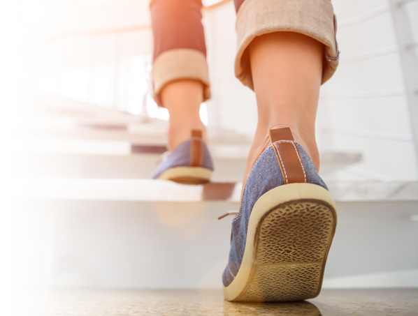 Woman wearing rubber soled shoes walking up stairs to prevent a fall